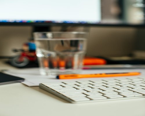 Water glass on an office desk next to a notebook